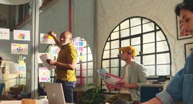People in creative office space looking at color printed documents with HP LaserJet Enterprise in background.