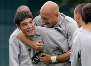 Celtic footballer Thomas Gravesen hugs his teammate Darren O'Dea from behind during a training session. Both are wearing grey T-shirts with the word "Carling" written on the front of it.