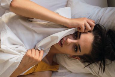 A woman lying in bed with a blanket covering half of her face