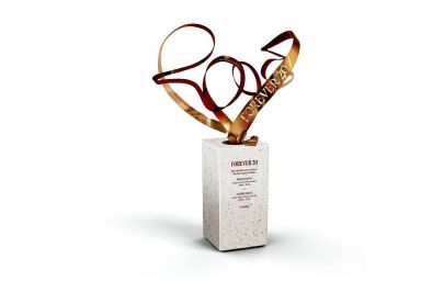 An abstract sculpture composed of intertwining metallic ribbons, rising from a minimalist white pedestal, displayed against a plain white background.