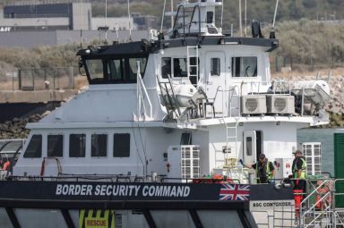Crew members stand aboard the British rescue ship BSC Contender after participating in a rescue operation at sea