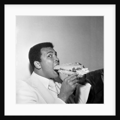 Muhammad Ali in Newcastle eating a Stottie cake 1977 by Dennis Hutchinson